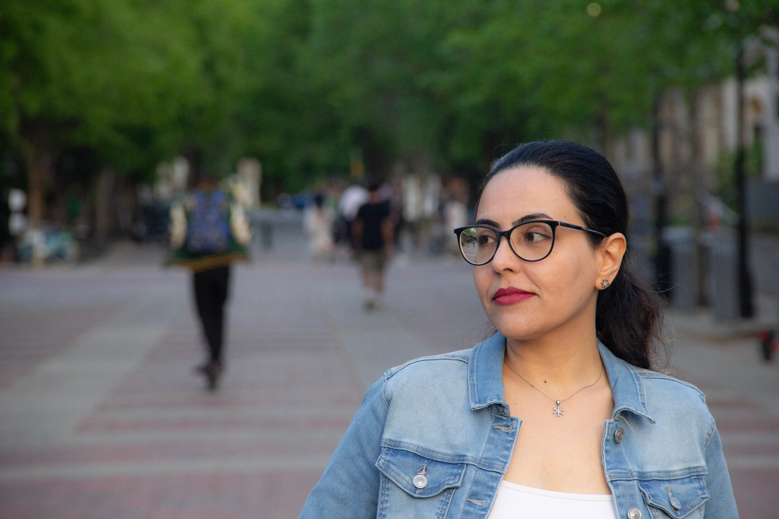 A woman in glasses walks down a walkway.