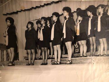 Choir members wearing matching outfits lined up on stage.