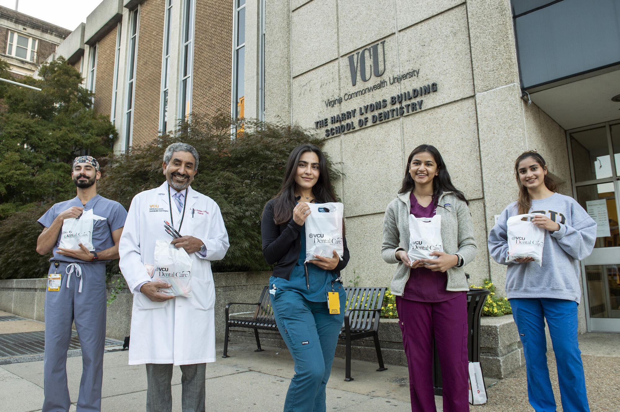 VCU students and faculty standing outside holding bags of dental supplies