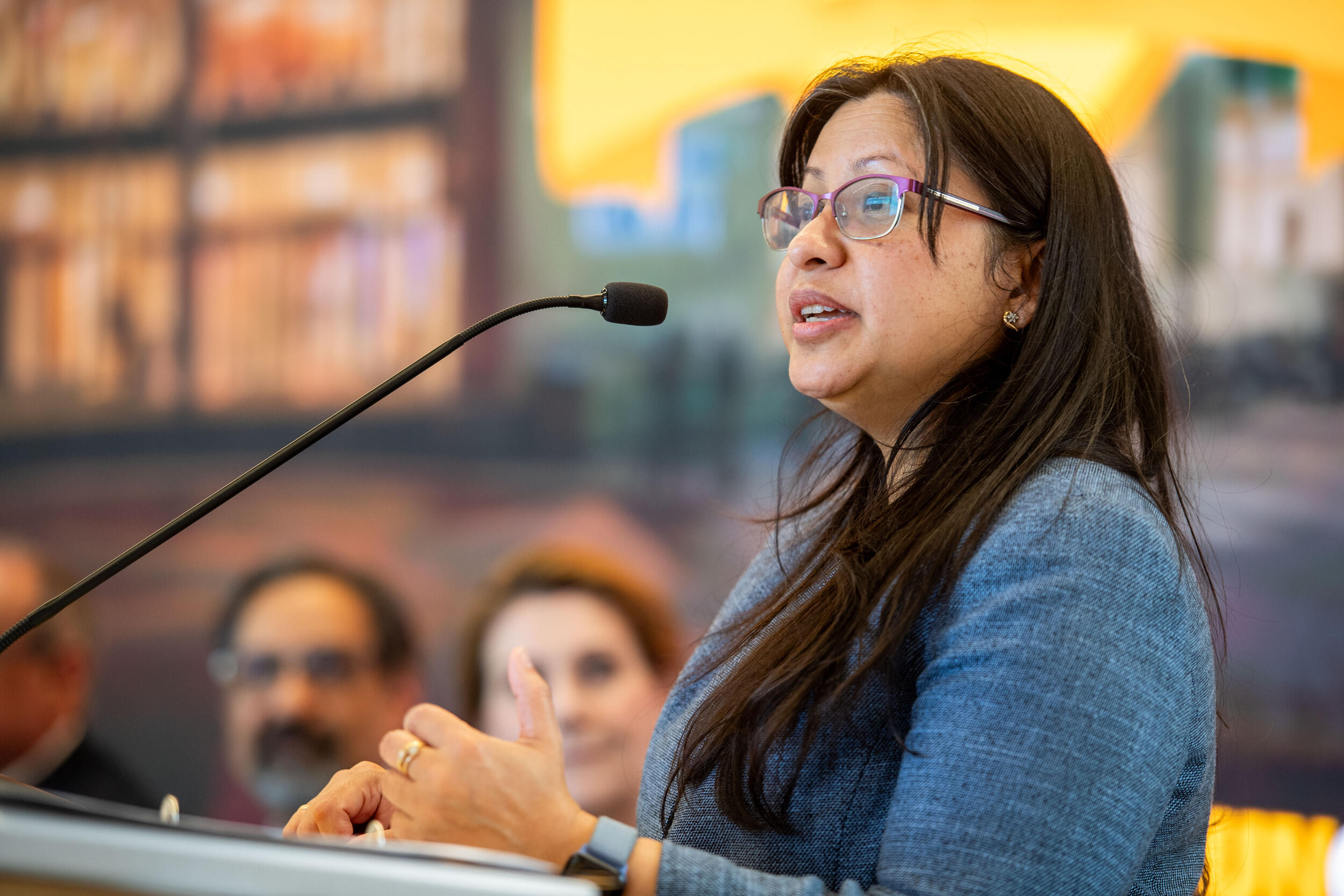 A photo of a woman standing behind a podium. 