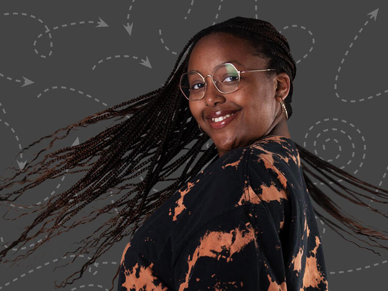 A woman wearing glasses turning around with her braided hair spinning around her. 