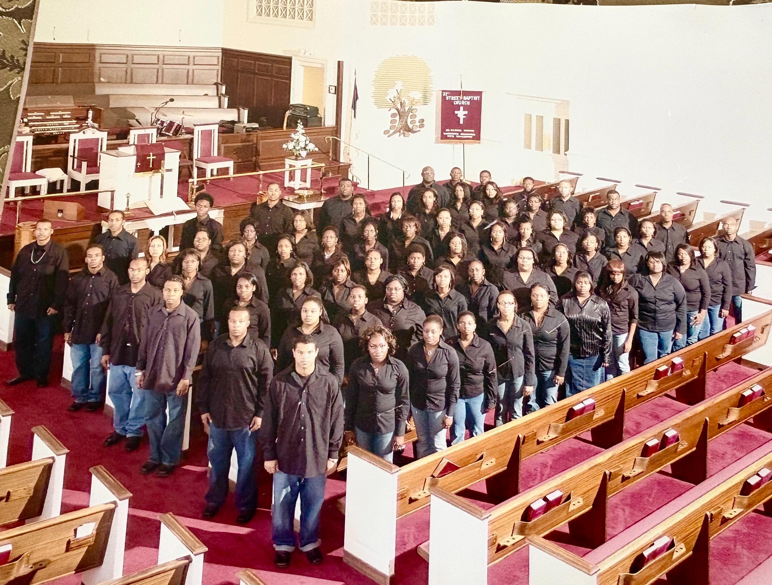 Rows of Black Awakening Choir members wearing matching outfits stand in the pews of a church.