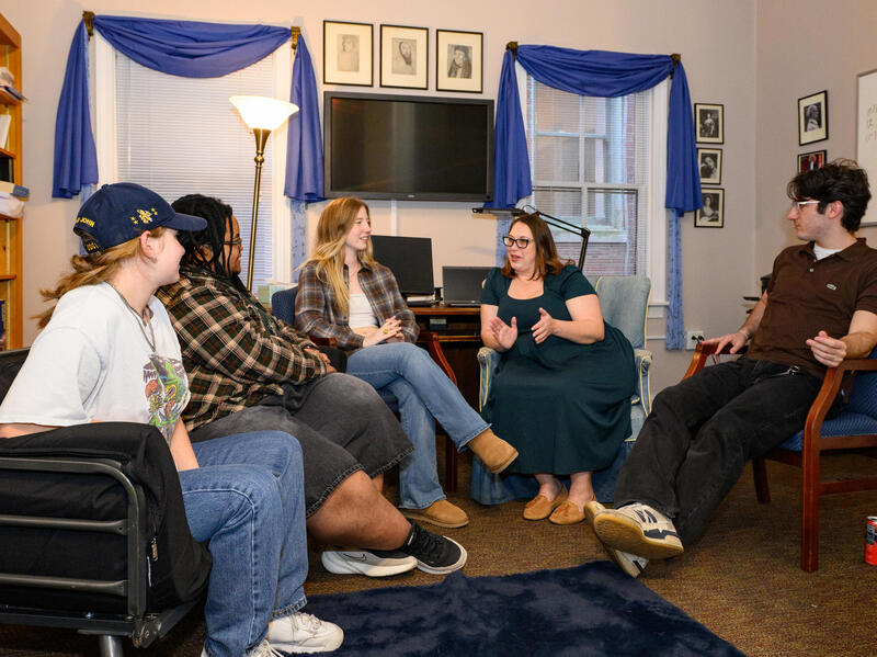 A photo of a group of five people sitting in a semi-circle. 