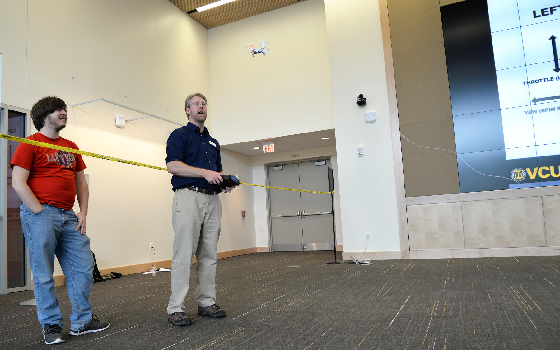 Eric Johnson, head of Innovative Media for VCU Libraries, pilots a drone while Bobby Cox, a physics major in the College of Humanities and Sciences, watches.