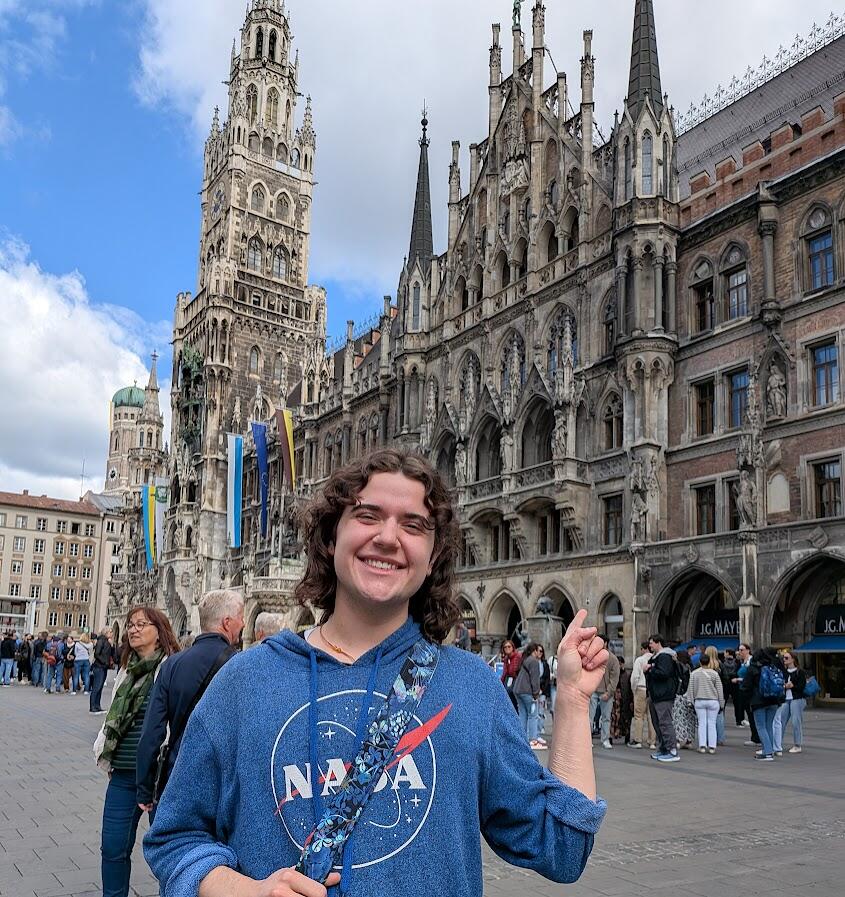 A photo of a man standing in front of an old gothic building. 