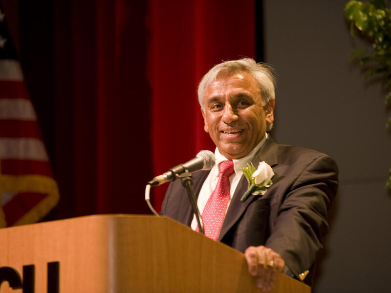 A photo of a man wearing a suit and tie standing at a podium 