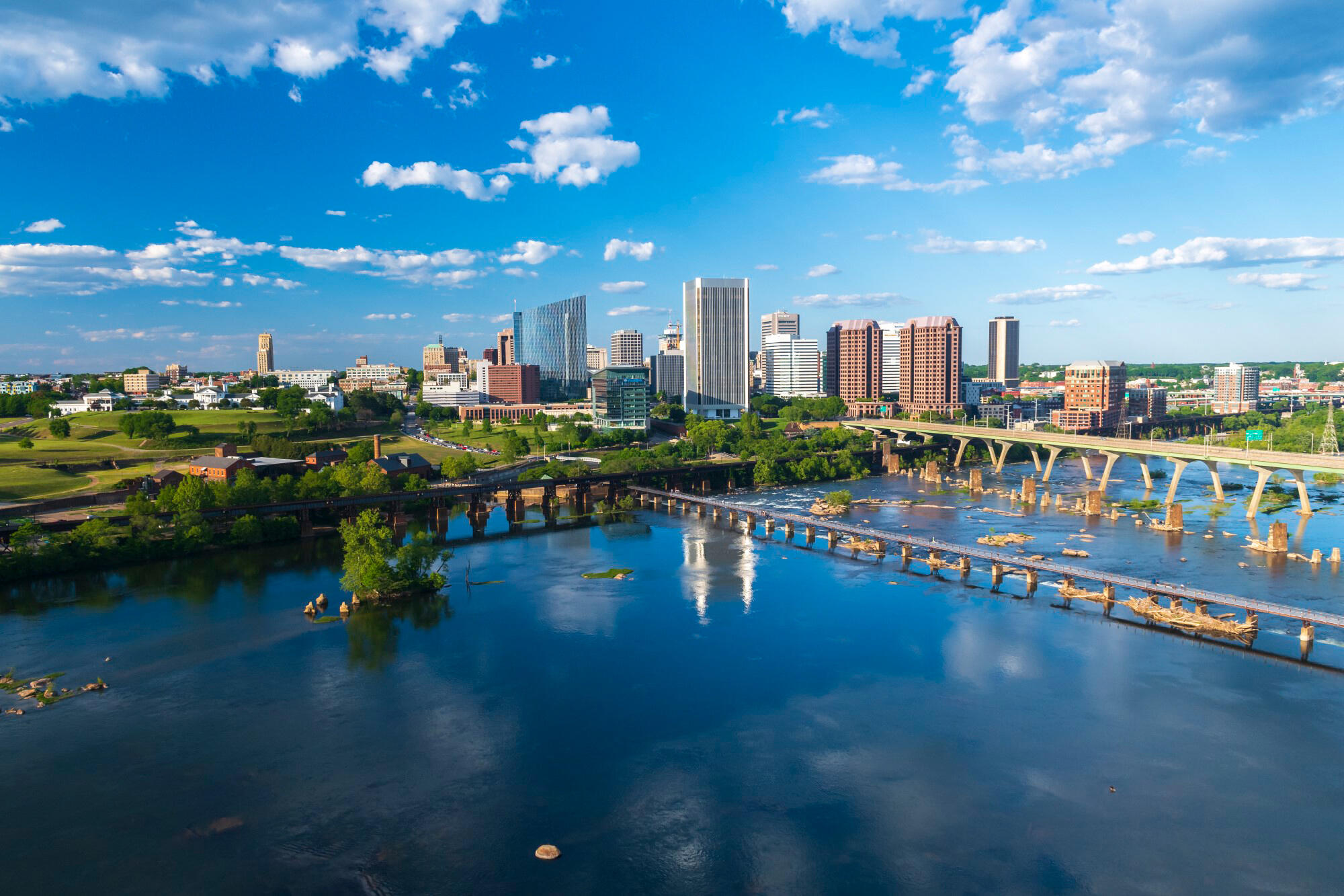 An aerial photo of the Richmond city skyline along a river under a blue sky.