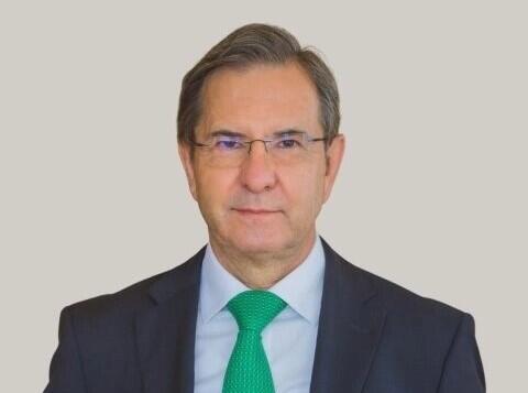 A photo of a man wearing a suit and tie from the chest up. 