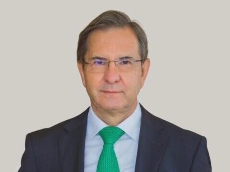 A photo of a man wearing a suit and tie from the chest up. 