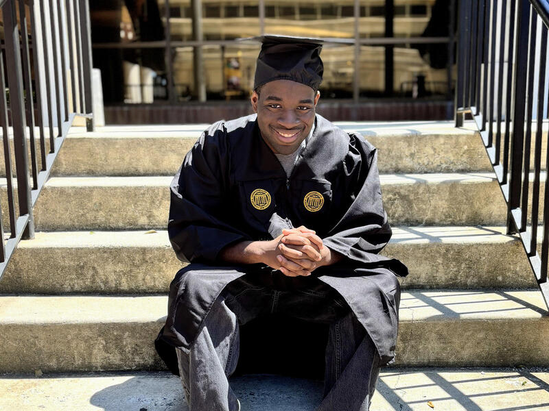 A photo of a man wearing a graduation cap and gown. 