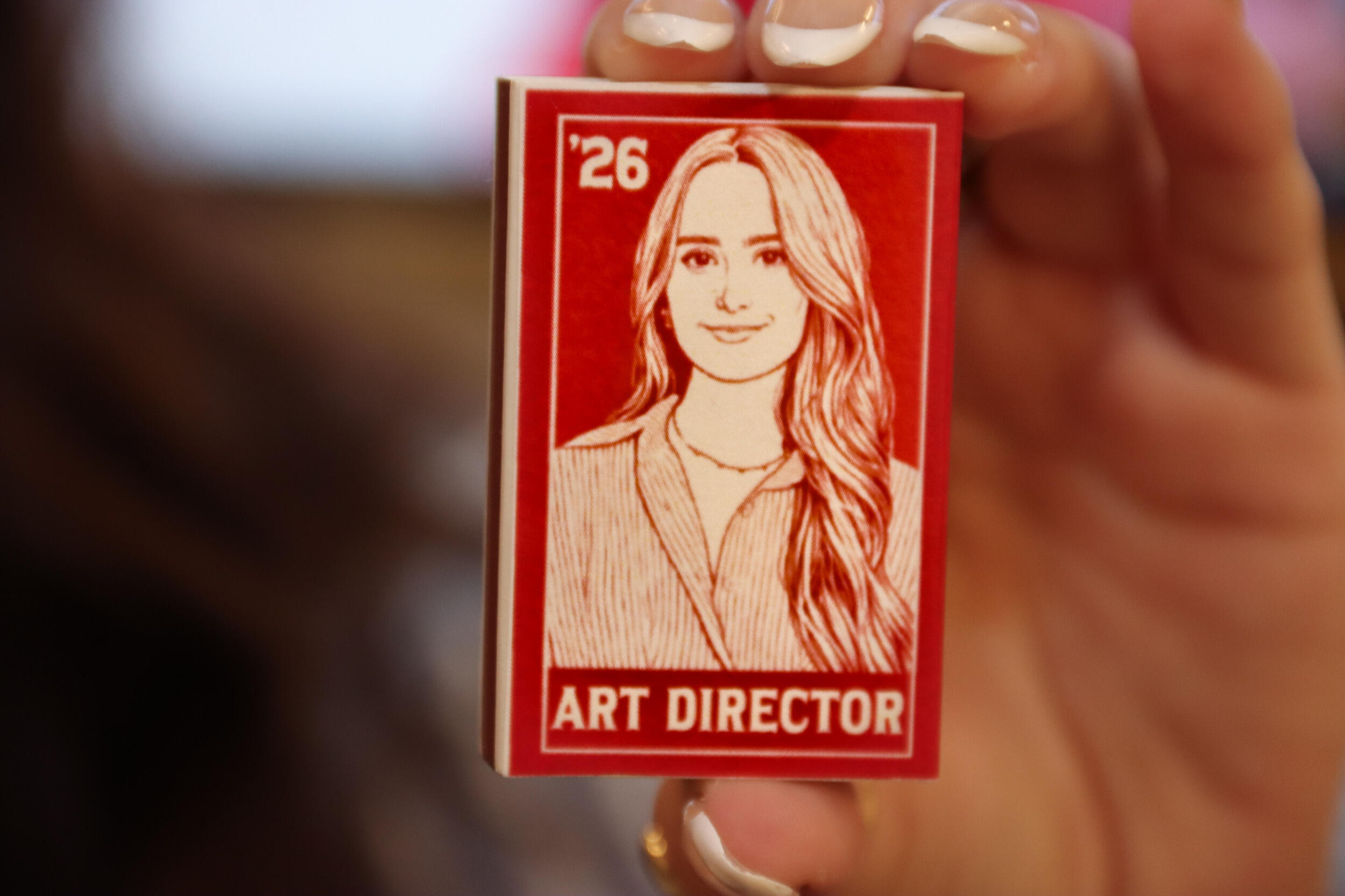 A red matchbox with a woman's image on it in white.